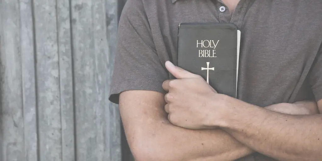 A man holds his bible against his chest.