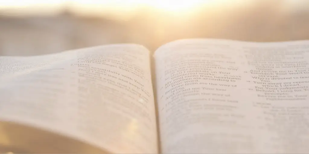 A bible sits open with the sunset in the background.