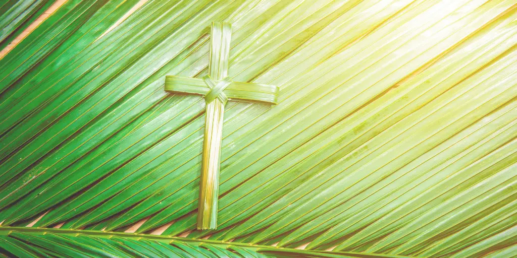 A cross made of palm fronds laying on top of a giant palm frond.