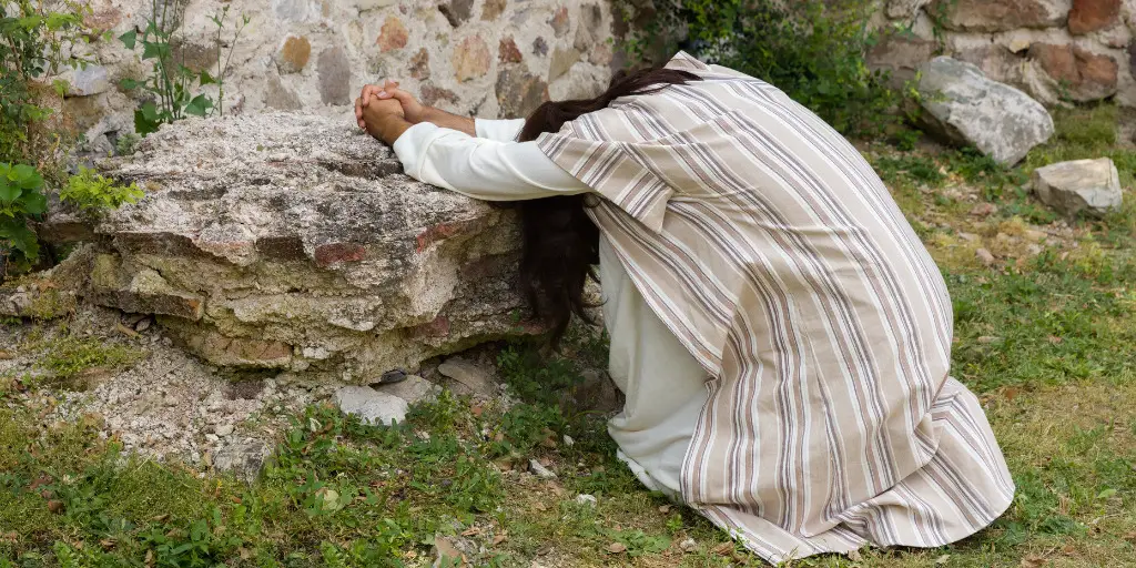 Jesus kneels in prayer.