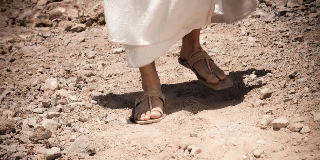 An image showing just the legs and feet of Jesus walking a dirt trail.