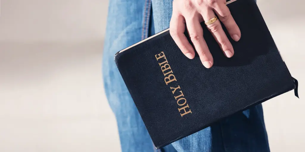 A man holds his closed bible as he walks.