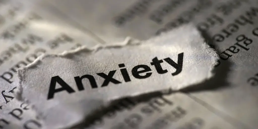 An image of the word "anxiety" on a thick torn piece of paper.