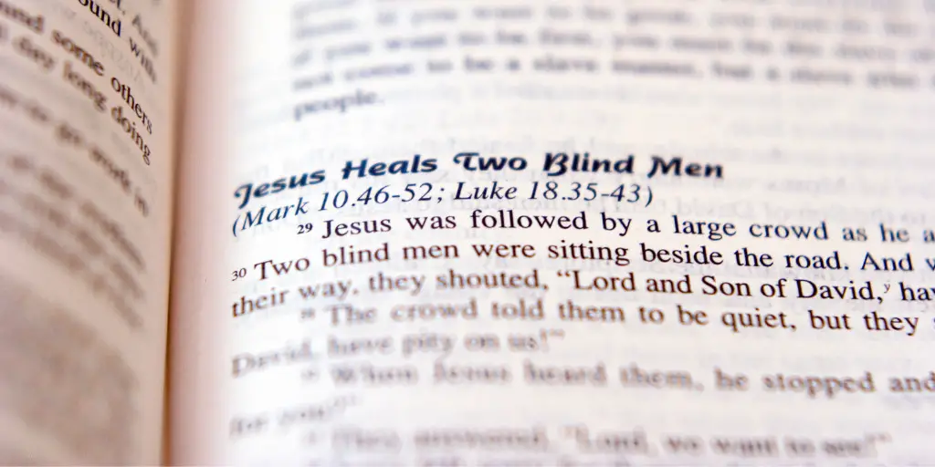 A close-up image of an open bible on a page that reads "Jesus Heals Two Blind Men"
