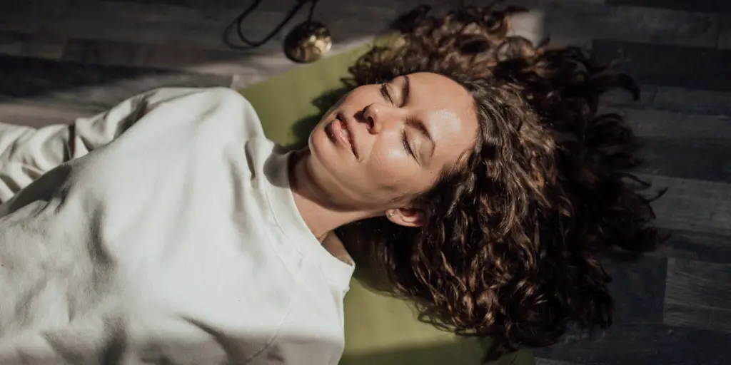 Woman relaxes while laying on a yoga mat.