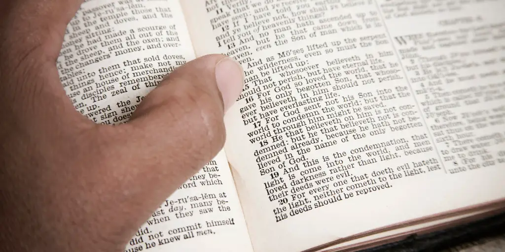 A man reads his open bible with his thumb keeping mark of the verse that reads "And as Moses lifted up the serpent in the wilderness, even so must the Son of man be lifted up"